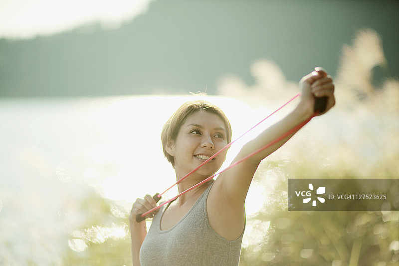 女人在湖边用橡皮筋锻炼图片素材