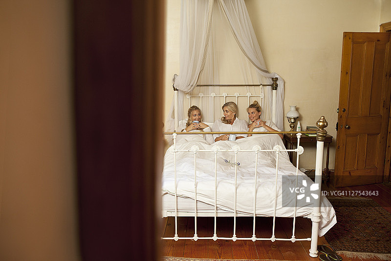 母亲和女儿在床上喝咖啡图片素材