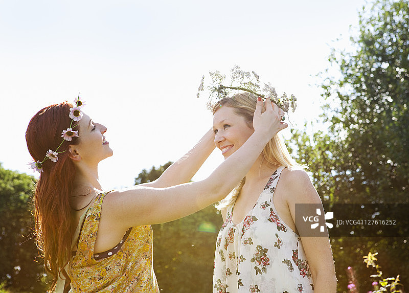 女人给朋友戴雏菊花环图片素材