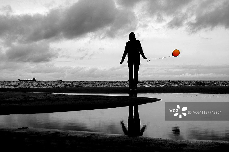 海滩上拿着气球的女子剪影图片素材