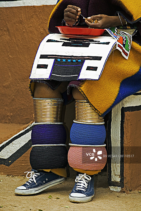 身着传统服饰的恩德贝勒族妇女在做珠饰，展示色彩鲜艳的已婚妇女腿环。莱塞迪文化村，靠近南非约翰内斯堡。图片素材