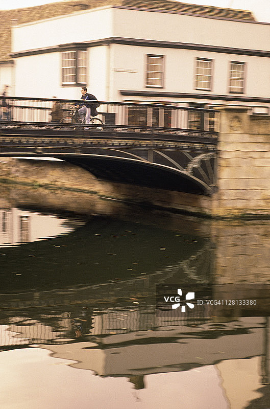 男子在英国剑桥的桥上骑自行车图片素材