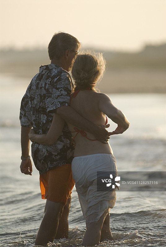 中年夫妇在海滩上挽着胳膊在水中行走图片素材