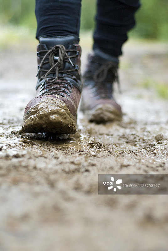 泥泞小路上徒步靴的特写图片素材