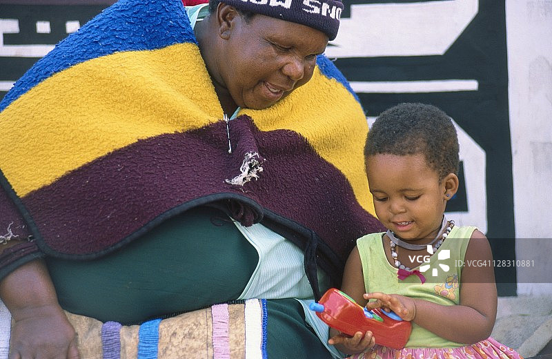 恩德贝勒族妇女和拿着玩具手机的小女孩图片素材