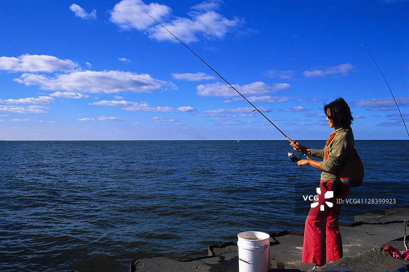 拿着钓鱼竿的女人，美国密歇根州大哈芬图片素材