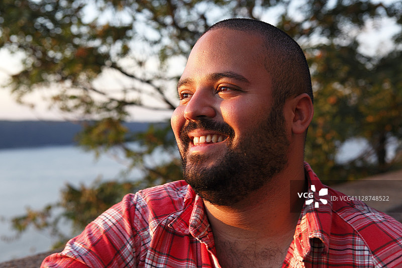 在纽约市日落时俯瞰哈德逊河的拉丁裔男人图片素材