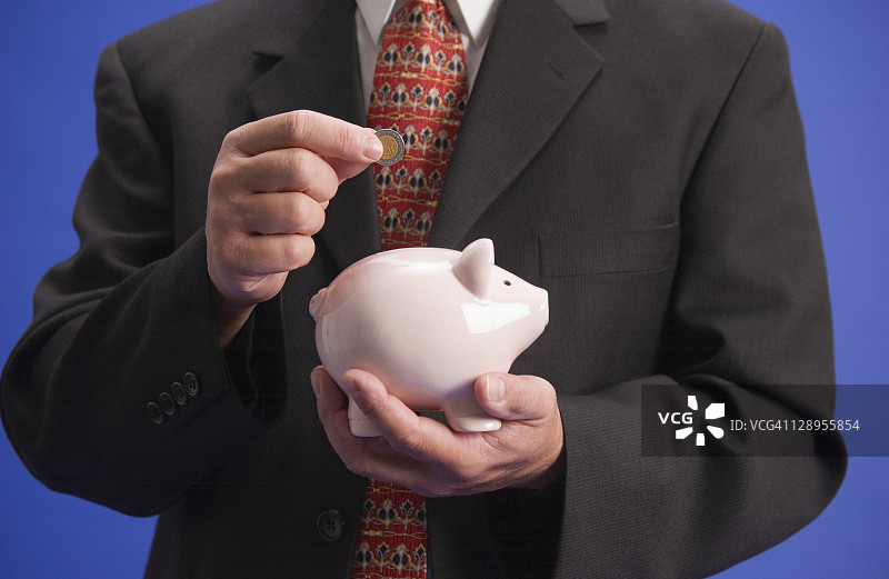 商人将墨西哥硬币放入存钱罐图片素材