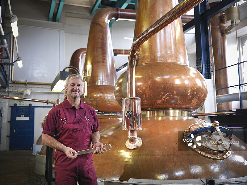 工人在酿酒厂的威士忌蒸馏器旁图片素材
