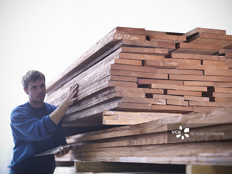工人在细木工车间检查成堆的硬木图片素材