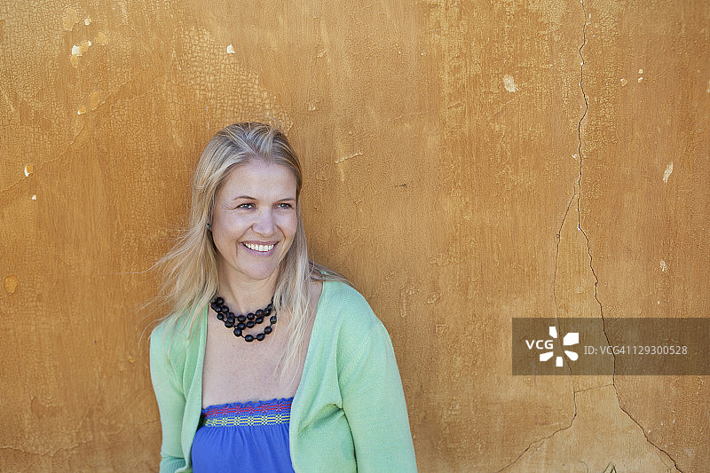 靠在墙上的微笑女人图片素材