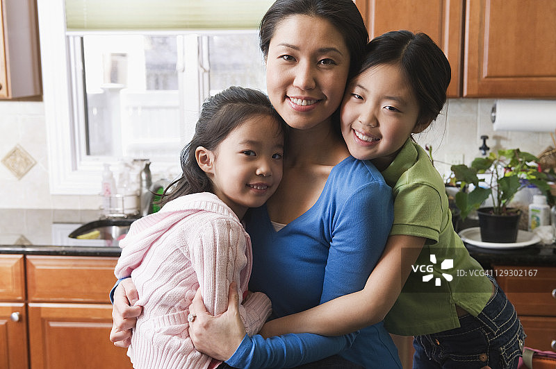 亚洲妈妈在厨房拥抱女儿们图片素材