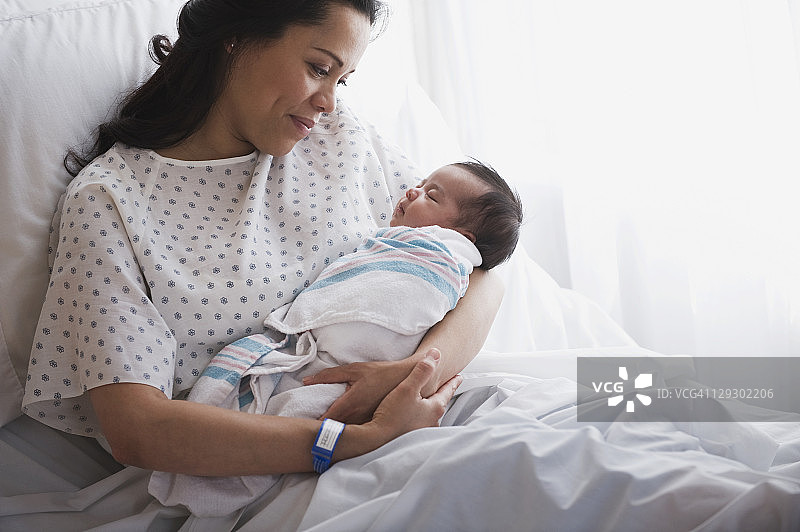 在医院病床上抱着新生女婴的母亲图片素材