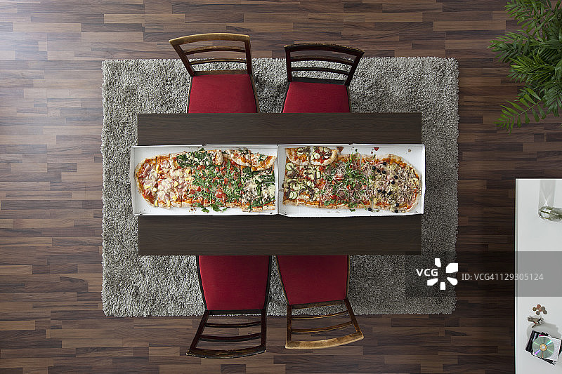 并排摆放在桌子上，长度横跨整个桌子的两块大披萨，俯视图图片素材