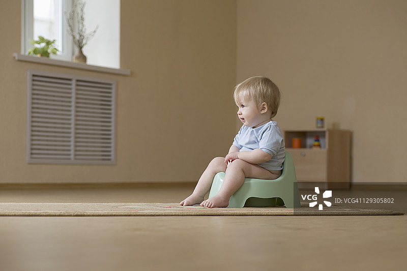 坐在便盆椅上，快乐地看向远方的小孩图片素材