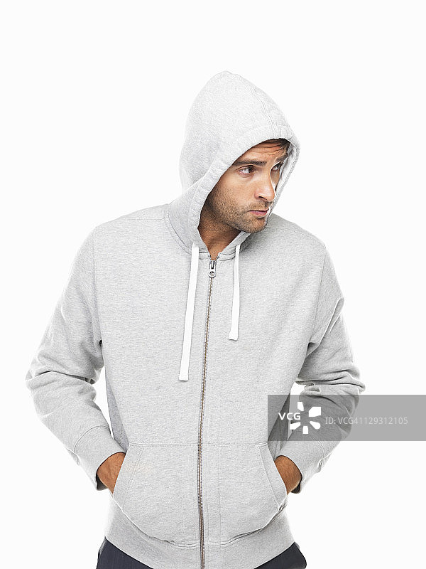 穿着连帽衫的年轻男人站着，双手插在口袋里图片素材