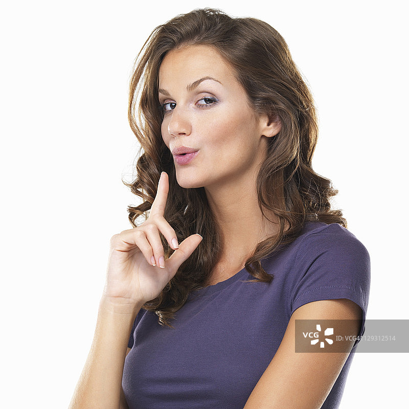 一位美丽女子用手做出枪的形状并吹掉想象中的烟雾的棚拍肖像图片素材