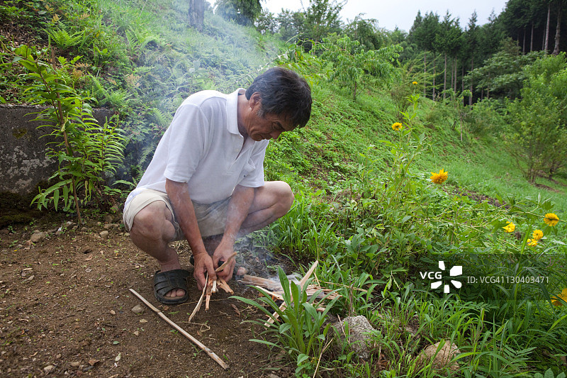 男人点燃篝火,迎接盂兰盆节逝者的灵魂图片素材