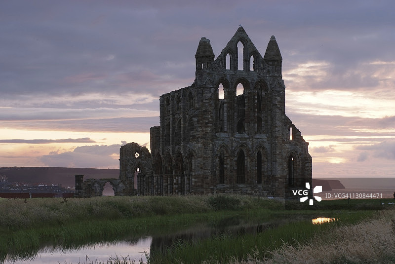 英国约克郡惠特比修道院在北海日落光芒中的遗址图片素材