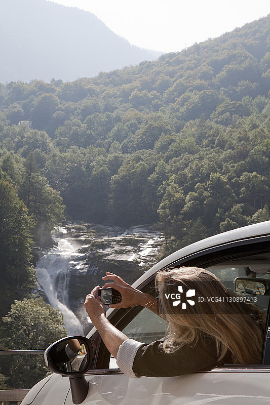 女人在车里拍摄森林和瀑布图片素材