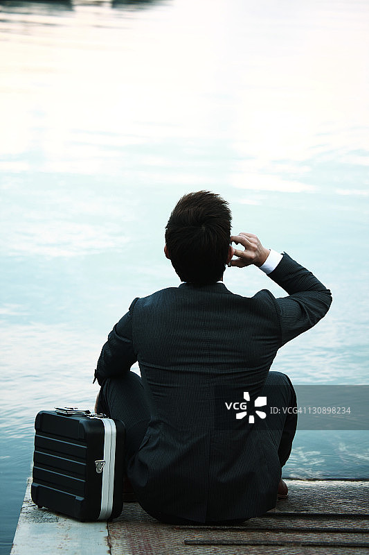 在湖边用手机交谈的商人图片素材