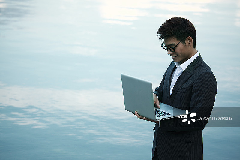 年轻商人带着笔记本电脑在湖边图片素材