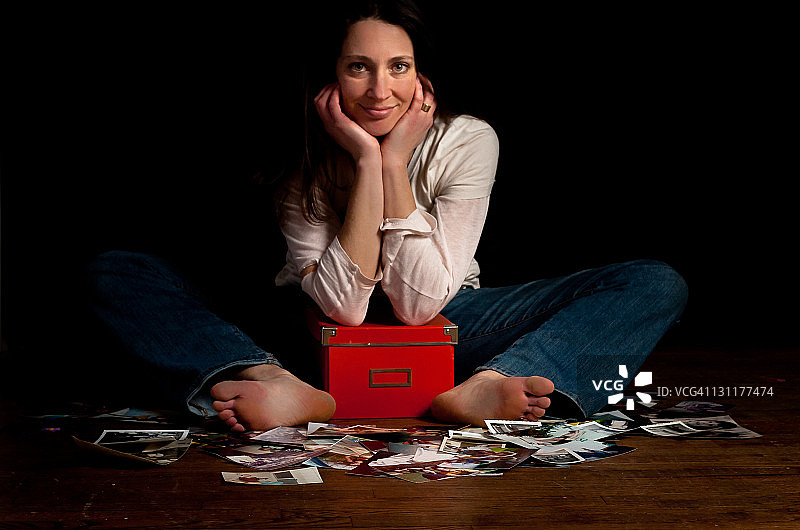 女人坐着，抱着一盒照片图片素材