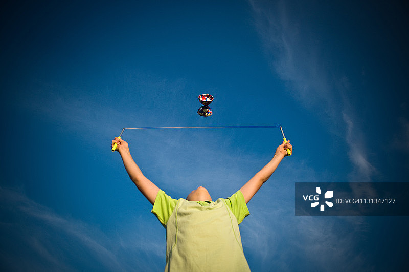 男孩在蓝天下玩空竹图片素材