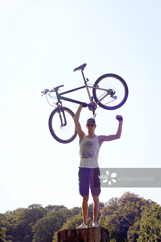 成年男子自信地将山地自行车抬到空中图片素材