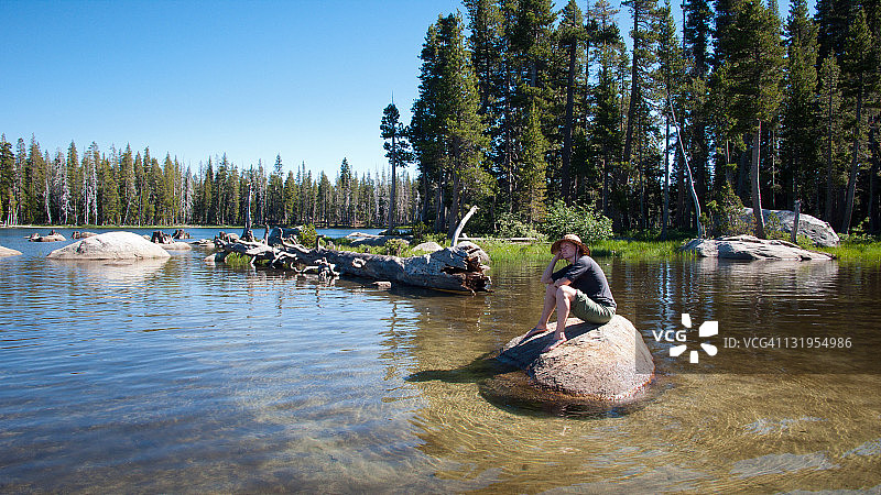 坐在湖边岩石上沉思的女人图片素材