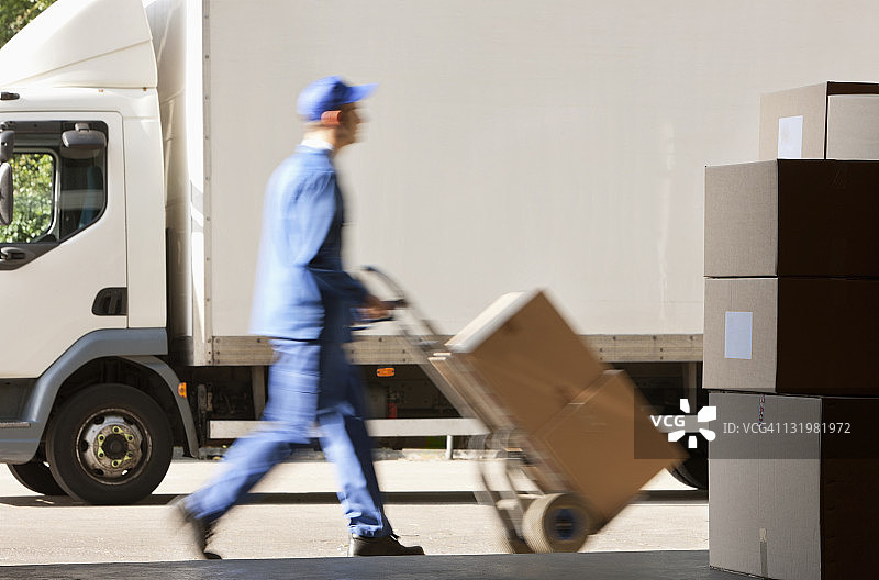 工人在仓库外推车的侧面照图片素材