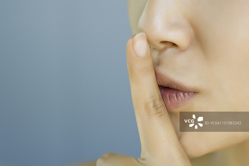 手指放在嘴唇上的年轻女人，裁剪图图片素材
