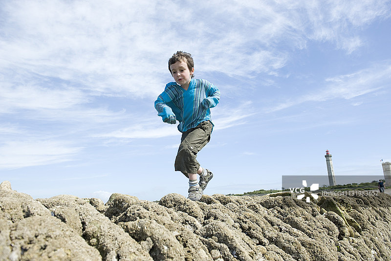 男孩沿着法国滨海夏朗德省雷岛的防波堤奔跑图片素材