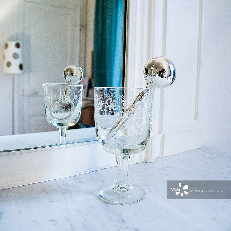 镜子前高脚杯中的银色拨浪鼓图片素材
