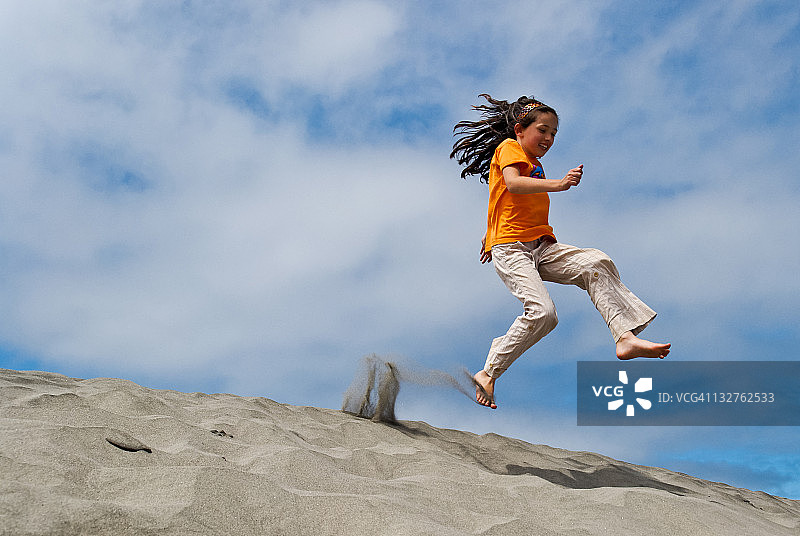女孩在沙丘上跳跃图片素材