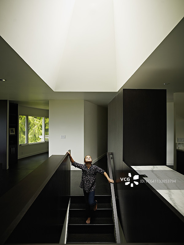 小女孩站在家里抬头看着天窗图片素材