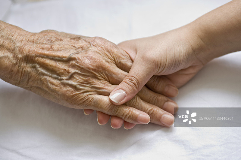 年轻女人的手牵着年长者的手图片素材