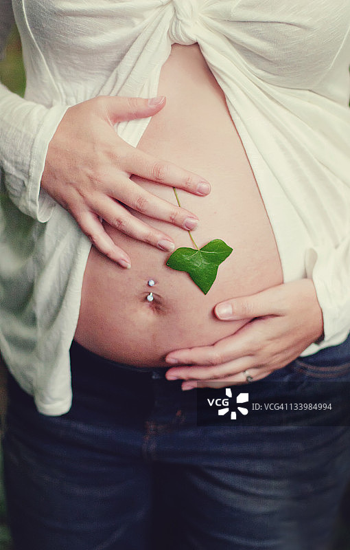 母亲隆起的腹部上的树叶图片素材
