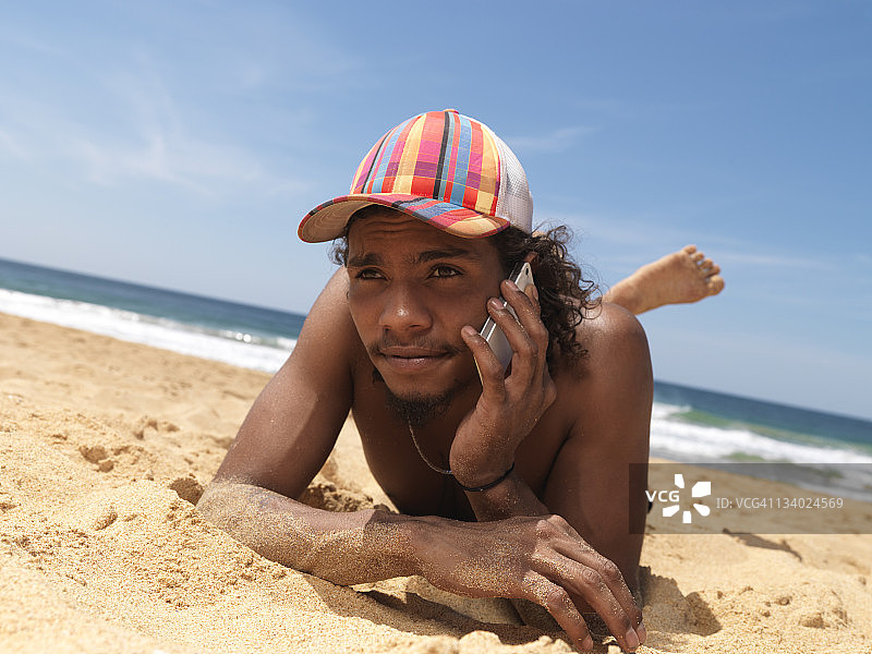 在海滩上玩智能手机的土著男孩图片素材
