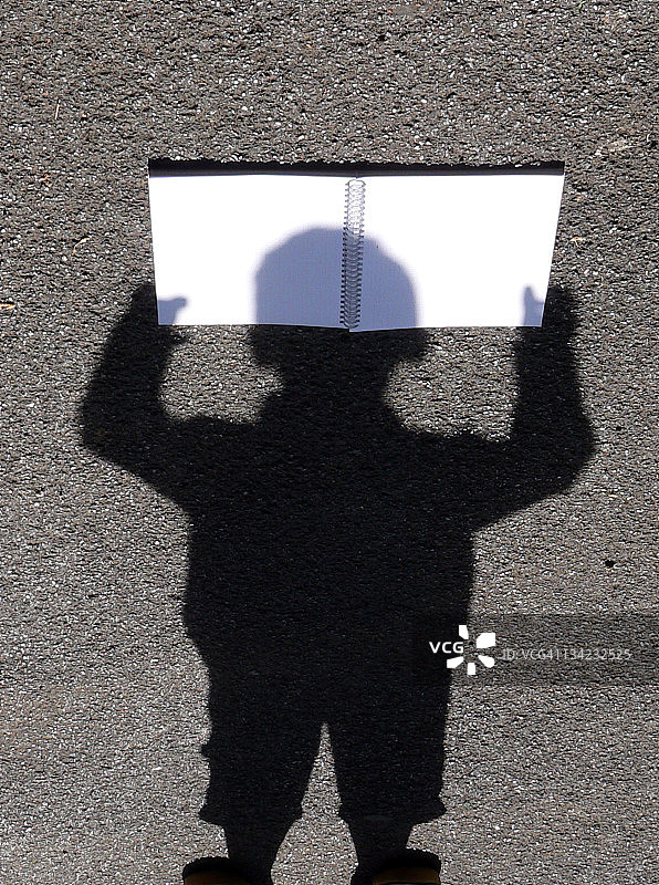 拿着螺旋书的男孩的影子图片素材