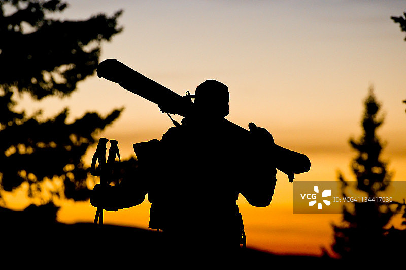 男子肩扛滑雪板徒步进入日落图片素材