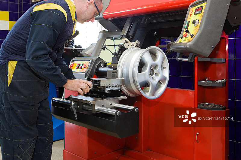 汽车修理店：汽车修理工更换轮胎图片素材