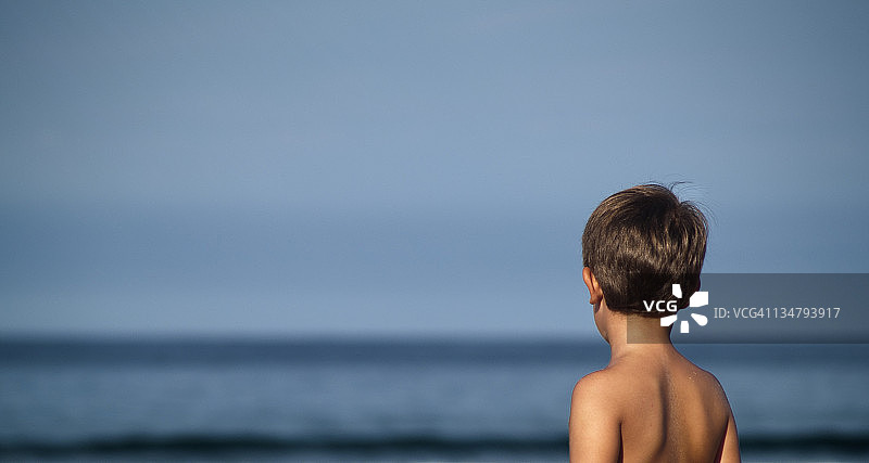 儿童凝视着地平线和大海图片素材