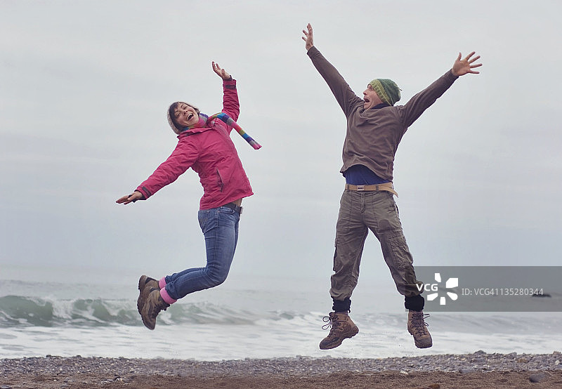 在沙滩上跳跃的男人和女人图片素材