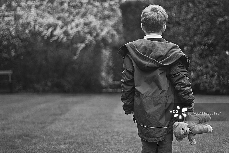 男孩拿着泰迪熊走路图片素材