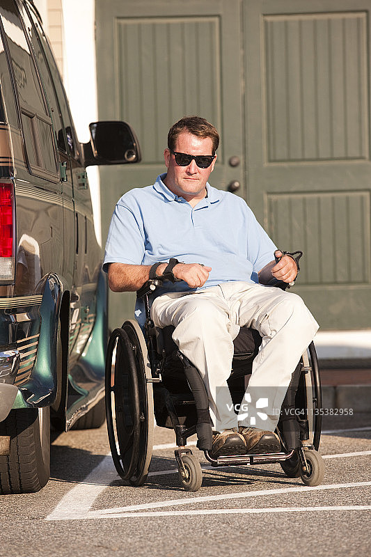 坐在轮椅上，停靠在无障碍面包车旁的脊髓损伤男子图片素材