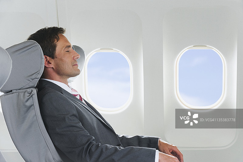 德国巴伐利亚慕尼黑：中年商务人士在商务舱飞机机舱内放松图片素材