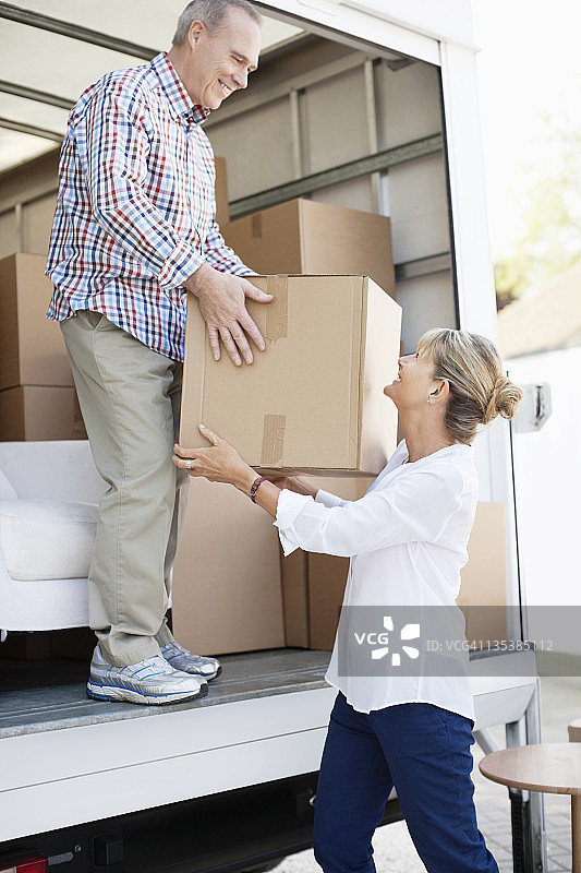 丈夫从搬家车里递给妻子一个盒子图片素材