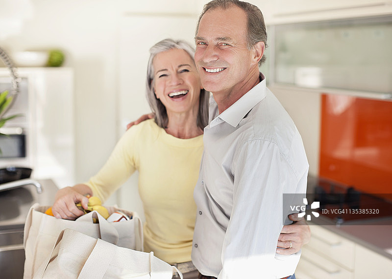 微笑的夫妇在厨房里整理可重复使用的购物袋图片素材