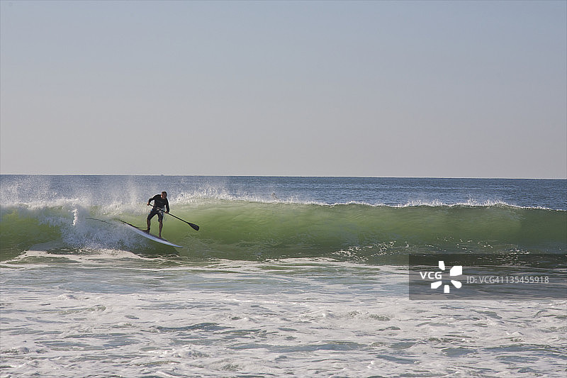在划桨板上乘风破浪的男人图片素材